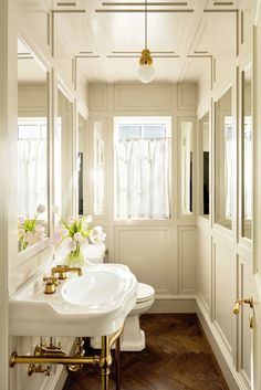 a white sink sitting under a window next to a toilet in a room with wooden floors