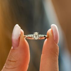 a close up of a person holding a ring with a diamond in it's middle