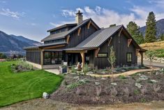 a large house sitting in the middle of a lush green field with mountains in the background