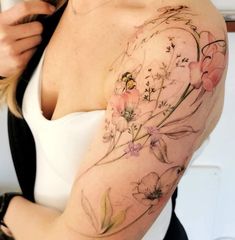 a woman with a flower tattoo on her arm and shoulder, showing off her breast