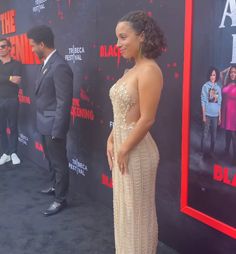 a woman in a dress standing next to a man on the red carpet at an event