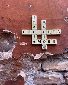 scrabble tiles spelling out the names of cities on a brick wall in italy