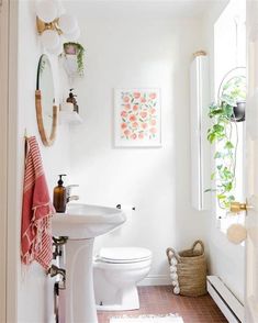 a white toilet sitting next to a bathroom sink under a mirror on top of a wall