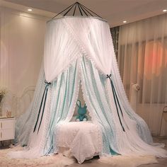 a canopy bed with white and blue drapes on it