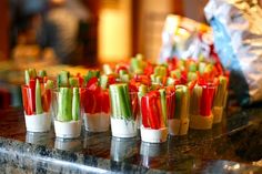 small cups filled with celery and carrots on a counter