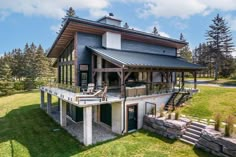 a large house sitting on top of a lush green field next to a tall forest