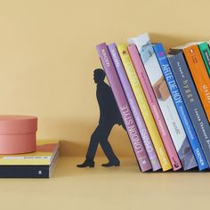 there is a book shelf with books on it and a toy man walking behind them