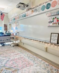 a room with a whiteboard and lights on the wall next to an area rug