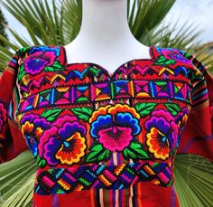 a woman's colorful dress on display in front of palm trees