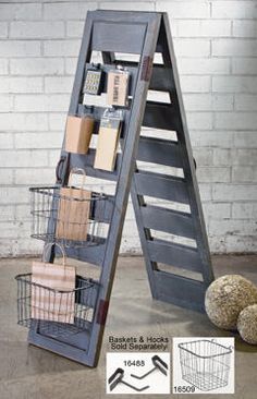 a ladder shelf with baskets on it next to a stuffed animal and other items in front of a brick wall