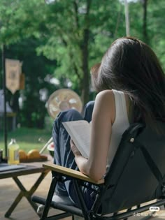 a woman sitting in a chair reading a book