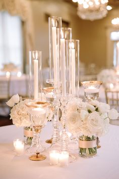 the centerpieces are filled with white flowers and candles for an elegant wedding reception