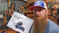 a man with a long beard holding up a sign in front of some woodworking tools