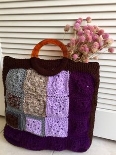 a crocheted bag sitting on the ground next to flowers