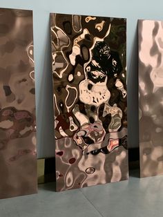 three metal panels with different shapes and sizes on the wall in front of each other