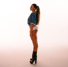 a woman in short shorts and high heeled boots is standing with her back to the camera