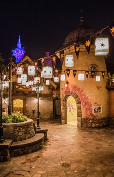 an outdoor area with lights and decorations on the walls, including lanterns hanging from buildings