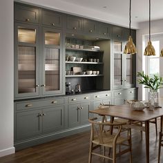 a dining room table and chairs in front of gray cabinets with gold lights hanging from the ceiling