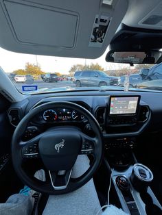 the interior of a vehicle with many cars parked in the parking lot and one person sitting at the steering wheel