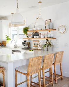 a kitchen with white counter tops and wooden chairs