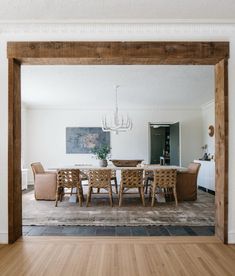 a dining room table with chairs and a chandelier hanging from the ceiling above it