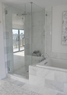 a bathroom with marble floors and white walls, including a walk in shower next to a large bathtub