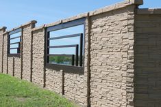 a brick wall with several windows on each side and grass in the foreground, against a blue sky