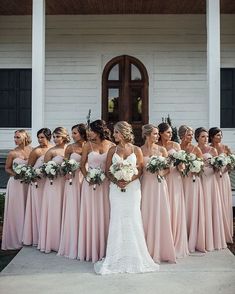 a group of bridesmaids standing in front of a white house holding bouquets