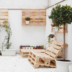 wooden pallet planters on the side of a white building with potted plants