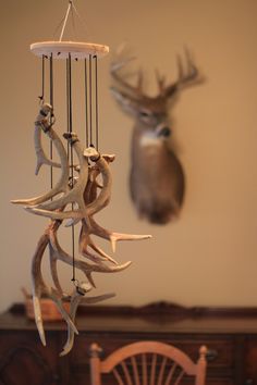 a deer head hanging from the side of a wall next to a wooden table and chair