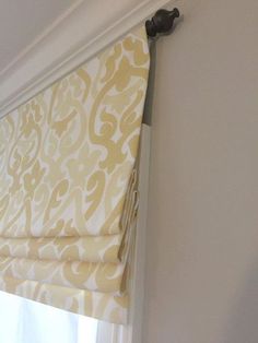 a yellow and white roman blind hanging on the side of a wall