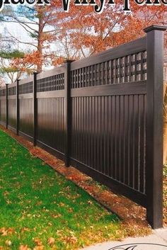 a black fence in the middle of a grassy area with trees and leaves around it