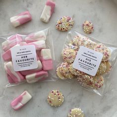 two bags of pink and white decorated cookies next to each other on a marble surface