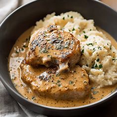 a bowl filled with meat and gravy next to mashed potatoes