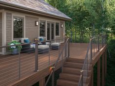 a deck with chairs and couches on it next to trees in the woods at dusk