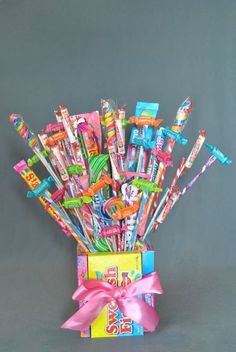 a bunch of candy sticks in a box with a pink bow on the front and bottom