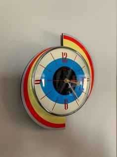 a clock that is on the wall with red, yellow and blue circles around it