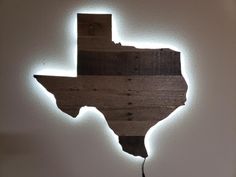 a wooden texas sign is lit up on the wall by string lights that are attached to it