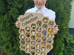 a young boy holding up a cardboard board with legos on it that says simon's collection