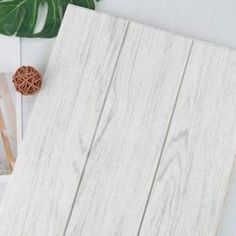 a white wooden paneled wall next to a plant and some pictures on the table