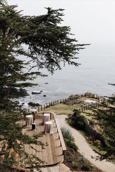 an outdoor dining area overlooking the ocean with tables and chairs set up on wooden planks