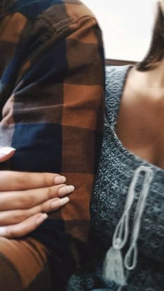 two people sitting next to each other with their hands on the back of one person's shoulder