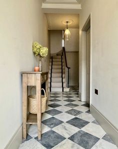 a hallway with black and white checkered flooring next to a wooden console table