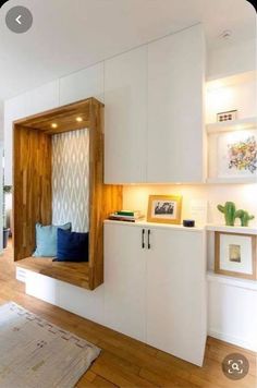 a room with white walls and wooden floors has a built - in storage unit on the wall