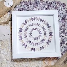 a white frame sitting on top of a pile of sea shells