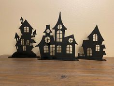 three black paper cut houses sitting on top of a wooden table