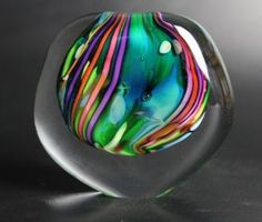 a colorful glass object sitting on top of a table next to a black surface with light coming through it