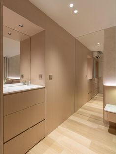 an empty bathroom with wooden floors and white counter tops on the wall, along with large mirrors