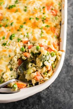 a casserole dish with broccoli, carrots and peas in it