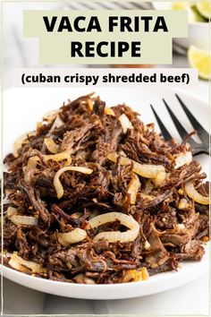 a white plate topped with shredded beef next to a fork and lemon wedged salad